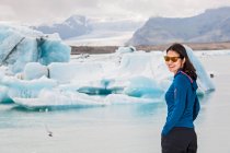 Jeune femme vêtue d'une veste blanche et lunettes sur un lac gelé. — Photo de stock