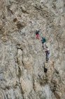 Vista de ángulo alto de amigos masculinos y femeninos que caminan en acantilado rocoso - foto de stock