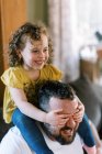 A father playing with his daughter on his shoulders in living room — Stock Photo