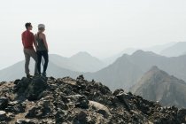 Couple regardant la vue depuis le sommet de la montagne contre un ciel dégagé pendant les vacances — Photo de stock