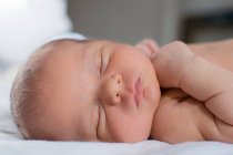 Neugeborenes Baby mit pummeligen Wangen und rosa Lippen schläft im Bett. — Stockfoto