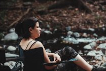 Жінка сидить на березі річки відпочиває — стокове фото