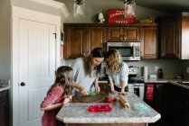 Mother making gingerbread houses with kids daughters at home — Stock Photo