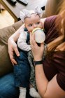 A woman with red hair feeding her baby daughter with a bottle — Stock Photo