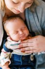 Молода мама, що тримає свого новонародженого, платить з любов'ю і посмішкою разом — стокове фото