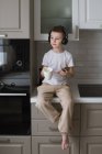 Junge hört Musik mit Kopfhörern, während er das Telefon benutzt — Stockfoto