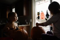 Дві дитини Гарбузове різьблення на Хеллоуїн в їхньому будинку — стокове фото