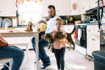 Little toddler girl holding her cute pet cat in her arms in kitchen — Stock Photo