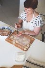 A woman in a white kitchen prepares traditional Russian dumplings from meat and dough — Stock Photo