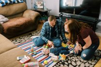 Uma jovem mãe e pai brincando com sua menina na sala de estar — Fotografia de Stock