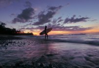 Surfer chica silueta contra colorido atardecer - foto de stock