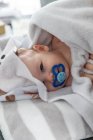Adorable baby boy wrapped in blankets sucking pacifier. — Stock Photo