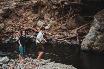 Geschwister amüsieren sich am Ufer eines Flusses — Stockfoto