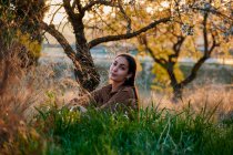 Портрет молодой женщины, сидящей на высоких травах на закате — стоковое фото