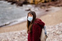Kaukasische junge Frau im Winter mit Gesichtsmaske am Strand — Stockfoto