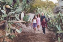 Famille mixte de quatre personnes marchant sur un sentier de cactus. — Photo de stock