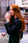 Young red-haired woman relaxing drinking coffee on the terrace of a bar — Stock Photo