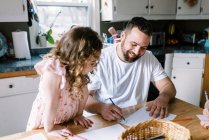 Un père et sa petite fille coloriant ensemble à la table de cuisine — Photo de stock