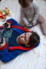 Baby-Mädchen sitzt neben Bruder, der auf Tablet spielt — Stockfoto