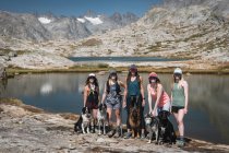 Smiling female friends with dogs standing at Titcomb Basin on sunny day — Stock Photo