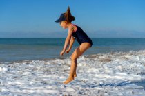 Chica joven saltando feliz en el mar en las vacaciones de verano. - foto de stock