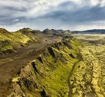 Vista aérea de montanhas localizadas perto de estrada e terreno seco em dia nublado na Islândia — Fotografia de Stock