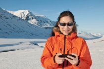 Mujer mensajes de texto en su teléfono inteligente en las montañas del norte de Islandia - foto de stock