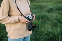 Pretty woman holding film camera in a field — Stock Photo
