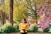 Young girl walking in the park with a photo camera in spring — Stock Photo