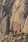 Amigos masculinos e femininos em pé sobre rochas contra penhasco enquanto caminham em férias — Fotografia de Stock