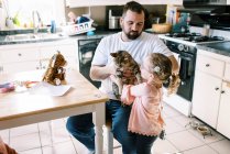 Little toddler girl holding her cute pet cat in her arms in kitchen — Stock Photo