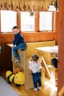 Due bambini piccoli che si arrampicano nella loro sala da pranzo in una mattina di sole — Foto stock