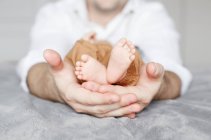 Closeup of father dad holding little newborn baby feet in his hands. — Stock Photo