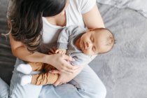 Child health. Proud mother holding rocking sleeping newborn infant baby son. Happy family bonding in bedroom. Home lifestyle authentic natural moment. View from top above overhead. — Stock Photo