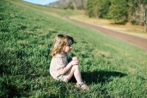 Little toddler girl sitting on the side of a dike in New England — Stock Photo