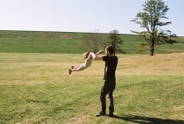 Une petite fille et son père jouant dans un champ herbeux près d'une digue — Photo de stock
