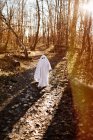 Дитина в костюмі привида, що бігає в парку восени протягом дня — стокове фото