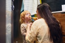 Beautiful woman brushes her teeth in the bathroom with her red-haired boy — Stock Photo