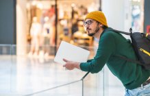 Moderner spanischer Mann mit Brille und Laptop posiert in Einkaufszentrum — Stockfoto