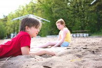 Молодий хлопчик і дівчинка грають на піску біля озера — стокове фото