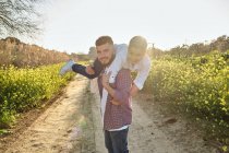 Glücklicher Vater blickt in die Kamera, während er mit seinem Sohn auf dem Feld spielt — Stockfoto