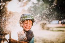 Мальчик играет на улице в брызги воды и смех — стоковое фото