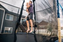 Pai saltando no trampolim com o filho da criança — Fotografia de Stock