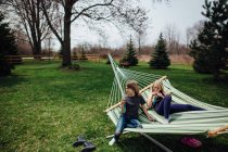Boy and girl relaxing on a hammock in backyard in spring — Stock Photo