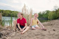 Menino e menina brincando na areia por um lago — Fotografia de Stock
