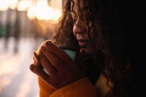 Жінка тримає чашку насолоджуючись гарячим напоєм на відкритому повітрі взимку — стокове фото
