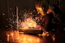 Female mechanic in protective helmet welding pieces — Stock Photo