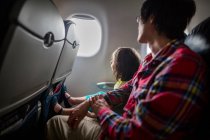 Маленькая девочка и отец сидят вместе в самолете и смотрят в окно. — стоковое фото