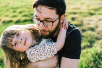 Glückliches kleines Mädchen, das seinen Vater mit Brille umarmt und lächelt — Stockfoto