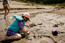 Молодая девушка играет на пляже, строит песчаный замок летом — стоковое фото